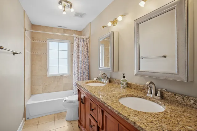 a bathroom with a granite countertop double vanity sink a mirror and a bathtub