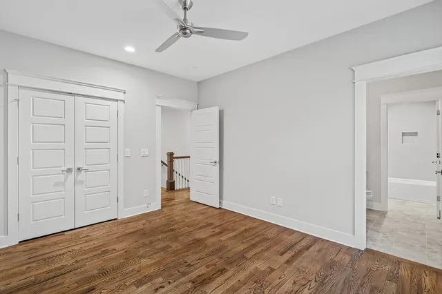 an empty room with wooden floor closet and windows