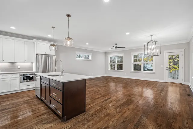 a kitchen with stainless steel appliances granite countertop a stove and a wooden floors