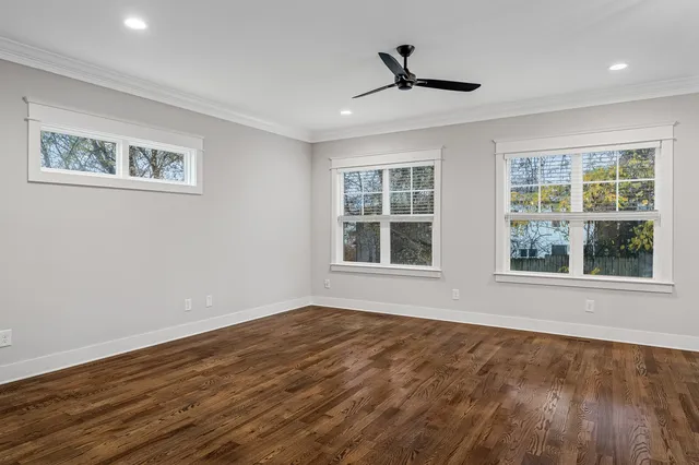 a view of an empty room with a window and wooden floor