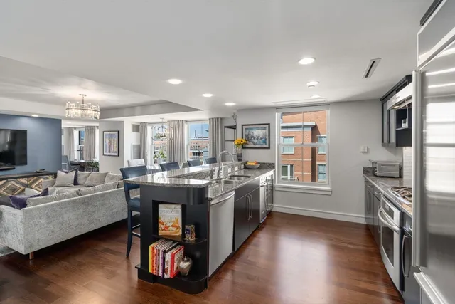 a large living room with stainless steel appliances granite countertop a couch and a wooden floor