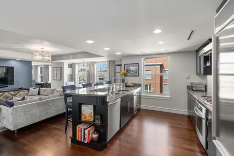 a large living room with stainless steel appliances granite countertop a couch and a wooden floor