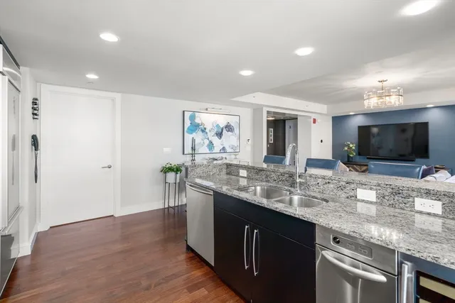 a kitchen with stainless steel appliances granite countertop a sink and a stove top oven with wooden floor