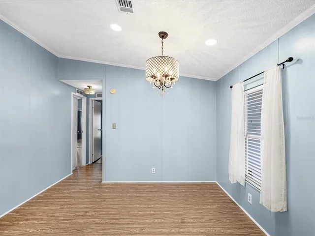 a kitchen with stainless steel appliances granite countertop a refrigerator a sink dishwasher a stove and a dining table with wooden floor