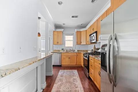 a large kitchen with a refrigerator a sink dishwasher a stove and white cabinets with wooden floor