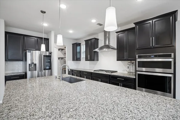 a kitchen with stainless steel appliances kitchen island granite countertop a refrigerator and a sink