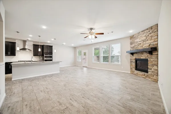 a view of an empty room with a kitchen and a fireplace