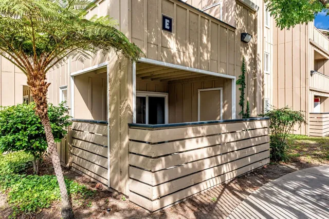 a view of a house with a large windows and flower plants