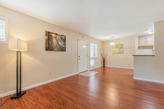 a view of an empty room with wooden floor and a window