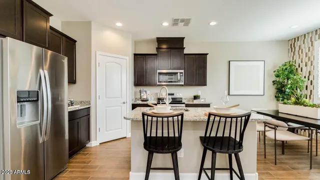 a kitchen with stainless steel appliances a table chairs refrigerator and microwave