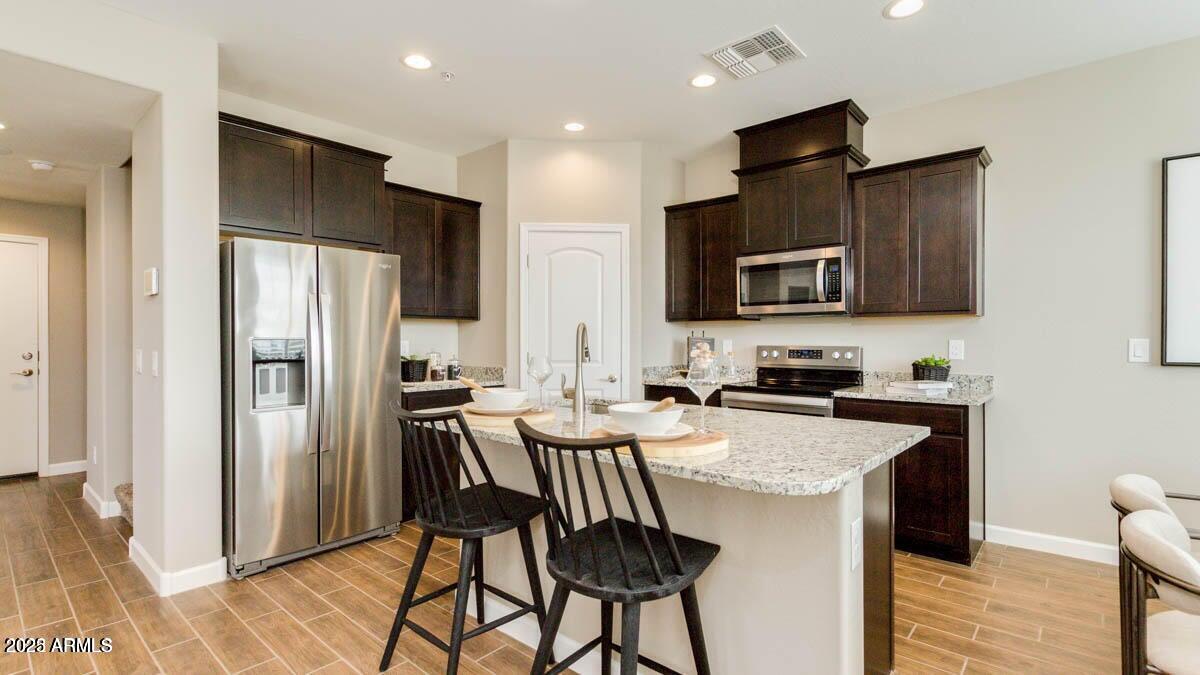 1255 North Arizona Avenue, Unit 1314 Chandler, AZ 85225 - Photo 4 of 23 a kitchen with stainless steel appliances granite countertop a refrigerator a stove a sink a dining table and chairs
