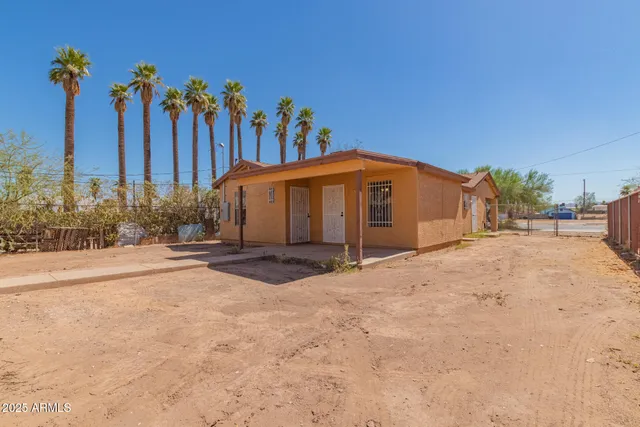 a view of a house with a yard and palm trees