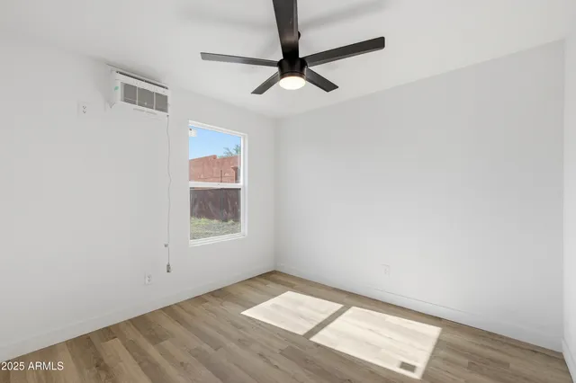 an empty room with a window and a ceiling fan