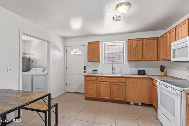 a kitchen with a white refrigerator a sink dishwasher with a dining table and chairs