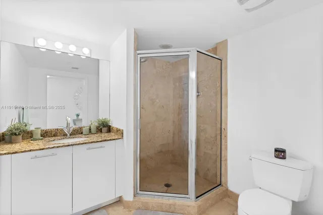 a bathroom with a granite countertop sink a toilet a mirror and shower