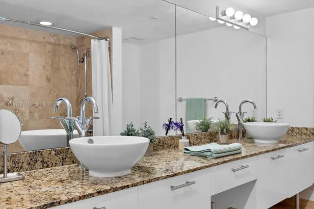 a bathroom with a granite countertop sink a mirror and a bathtub