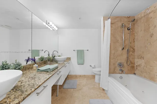 a bathroom with a granite countertop tub sink and mirror