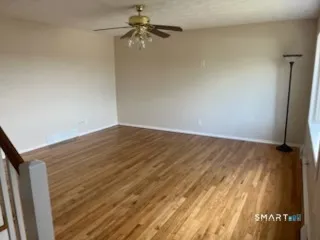 a view of a room with wooden floor and a ceiling fan