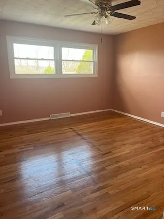 an empty room with wooden floor and windows