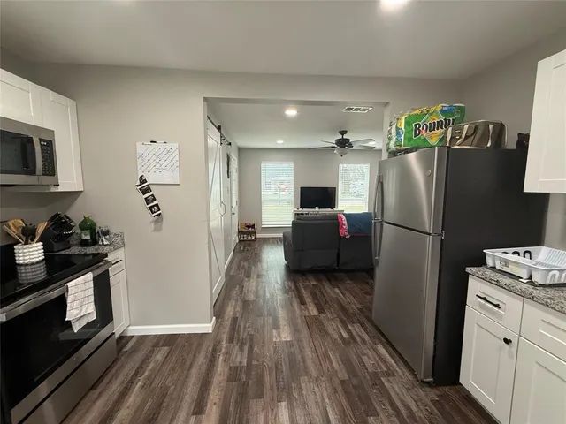 a kitchen with a refrigerator a stove top oven and wooden floor