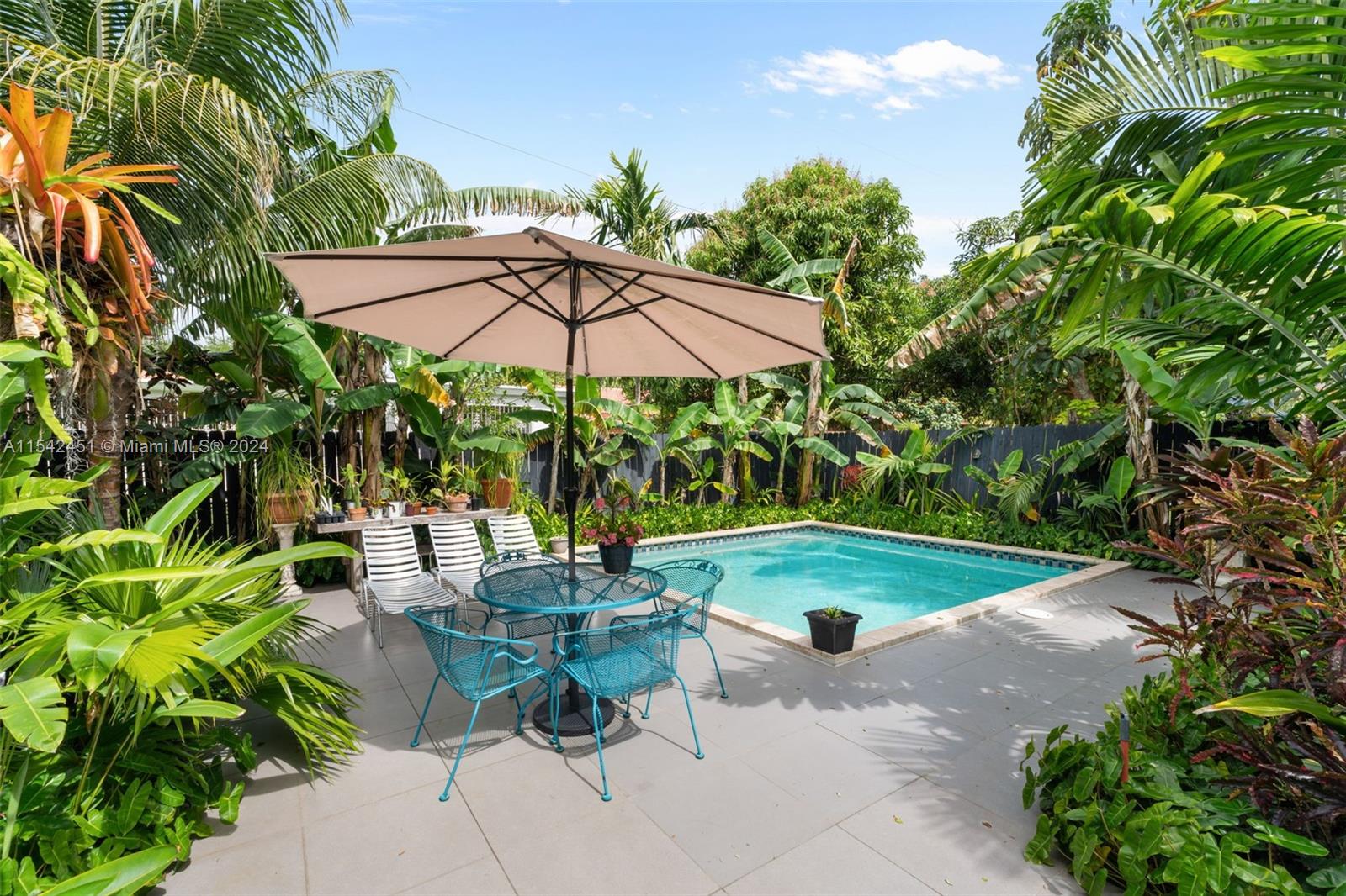 a view of pool with lawn chairs under an umbrella