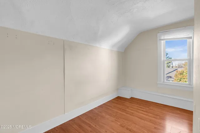 an empty room with wooden floor and window