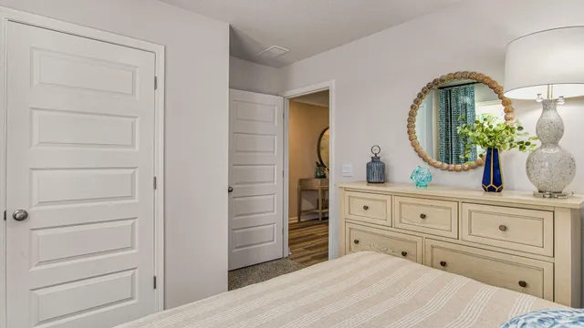 a bedroom with a bed and a mirror on the dresser
