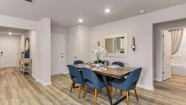 a kitchen with stainless steel appliances kitchen island granite countertop a stove a sink a refrigerator and white dining table with wooden floor