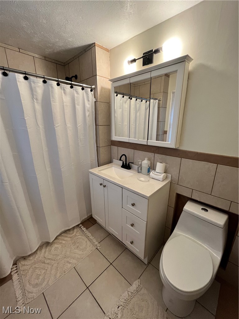 1048 Pembrook Road Cleveland, OH 44121 - Photo 19 of 26 Bathroom with tile walls, vanity, a textured ceiling, tile patterned flooring, and toilet