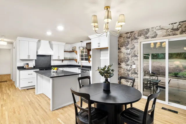 a kitchen with stainless steel appliances kitchen island granite countertop a sink a stove a dining table and chairs