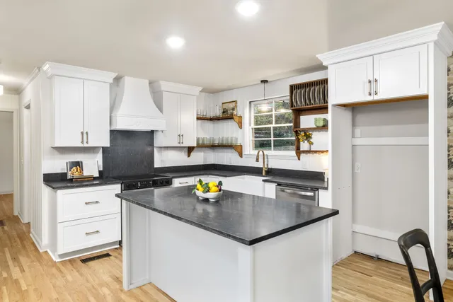 a kitchen with stainless steel appliances a sink a stove and white cabinets with wooden floor