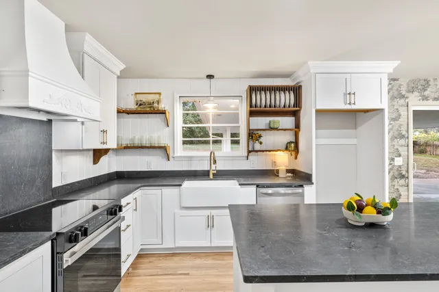 a kitchen with stainless steel appliances granite countertop a stove and white cabinets