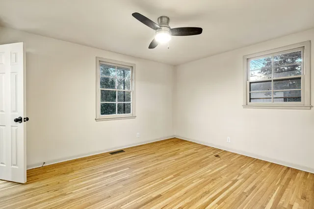 a view of empty room with wooden floor and fan