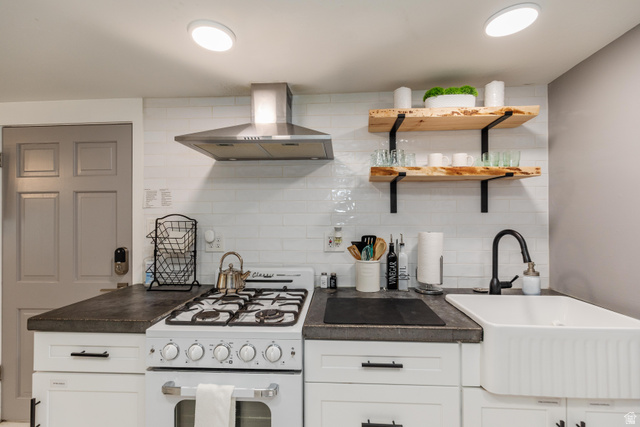 130 North 100 East Logan, UT 84321 - Photo 22 of 35 Kitchen featuring white subway tile backsplash, white cabinetry with dark hardware, dark countertops, and a white farmhouse sink