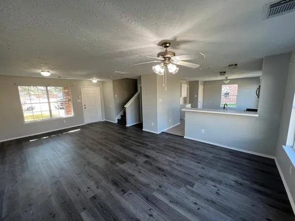 a view of an empty room with a window and wooden floor