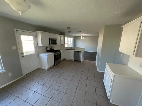 a large white kitchen with a sink a microwave and a stove