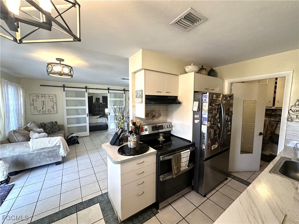 100 Davis Road Lehigh Acres, FL 33936 - Photo 4 of 32 a kitchen with a refrigerator and a stove