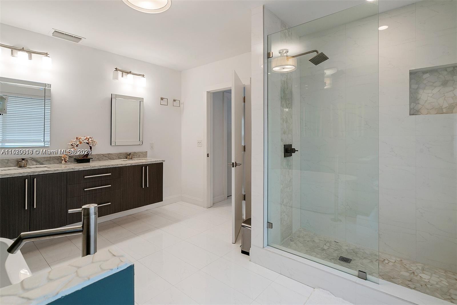 5250 Alton Road Miami Beach, FL 33140 - Photo 11 of 30 a bathroom with a sink a light fixture and a glass door