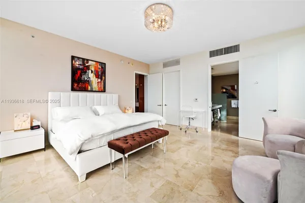 a spacious bedroom with a bed a couch and a chandelier