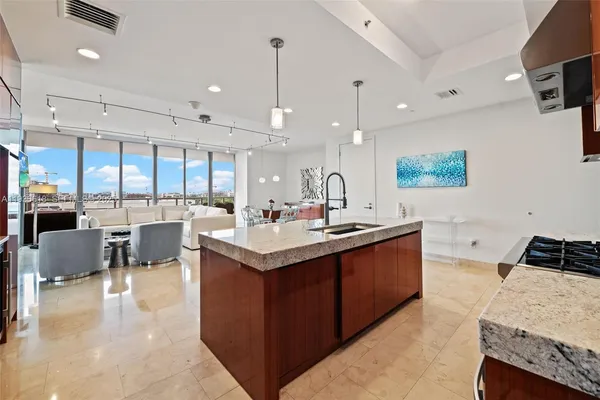 a large kitchen with a large counter top space a sink stainless steel appliances and cabinets