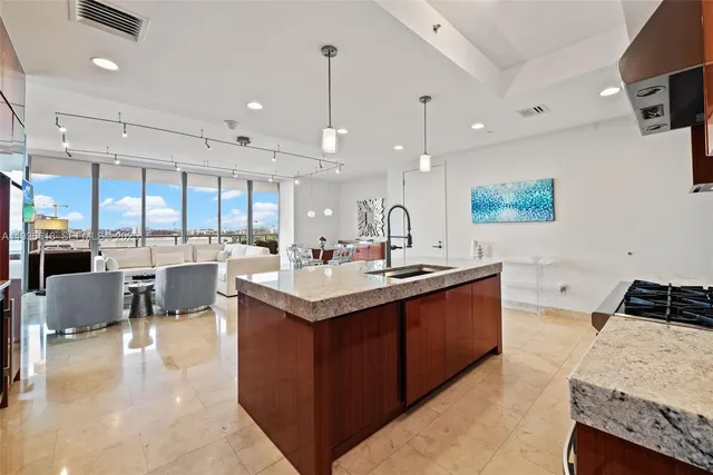 a large kitchen with a large counter top space a sink stainless steel appliances and cabinets