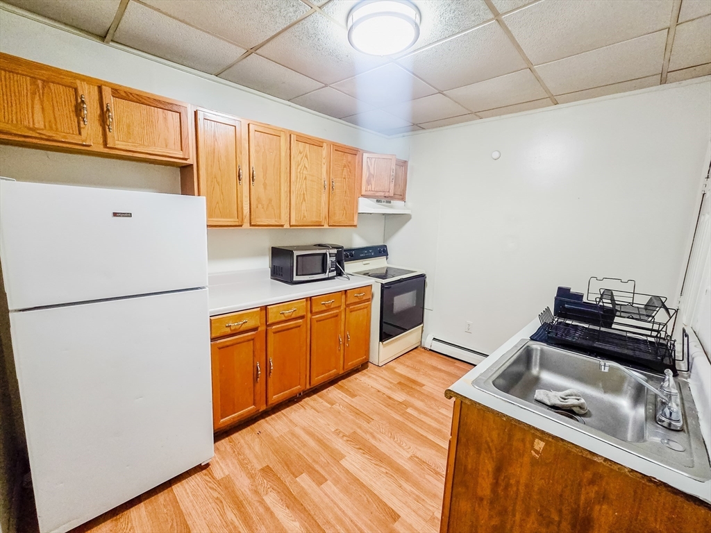 118 Jefferson Street Fall River, MA 02721 - Photo 3 of 34 a kitchen with a refrigerator a stove a sink dishwasher and wooden cabinets with wooden floor