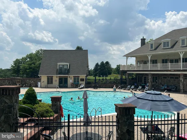 a front view of a house with swimming pool and plants