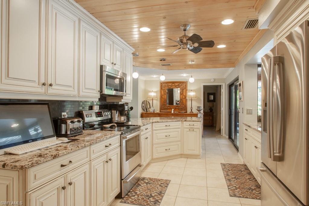 4525 North Road Naples, FL 34104 - Photo 5 of 33 a kitchen with stainless steel appliances granite countertop a refrigerator a sink dishwasher and white cabinets with wooden floor
