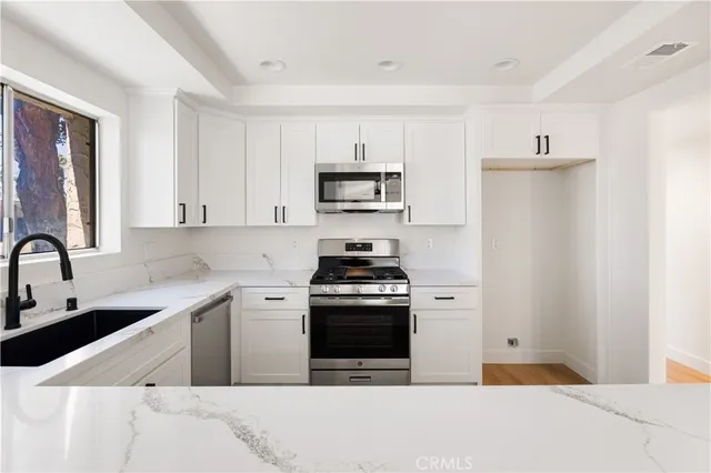 a kitchen with stainless steel appliances a stove a sink and a refrigerator