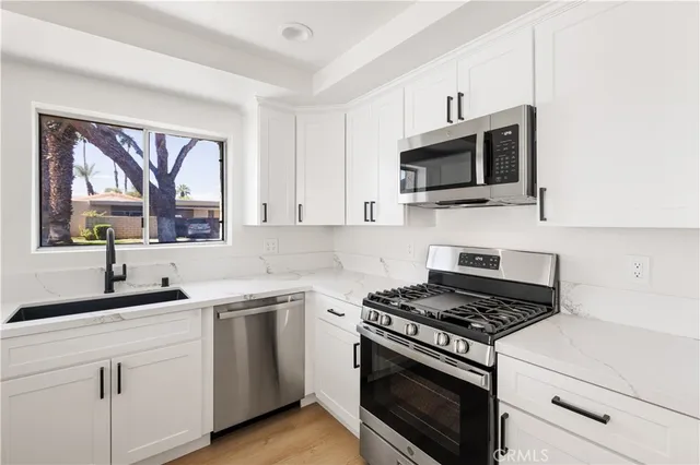 a kitchen with cabinets stainless steel appliances a sink and a window