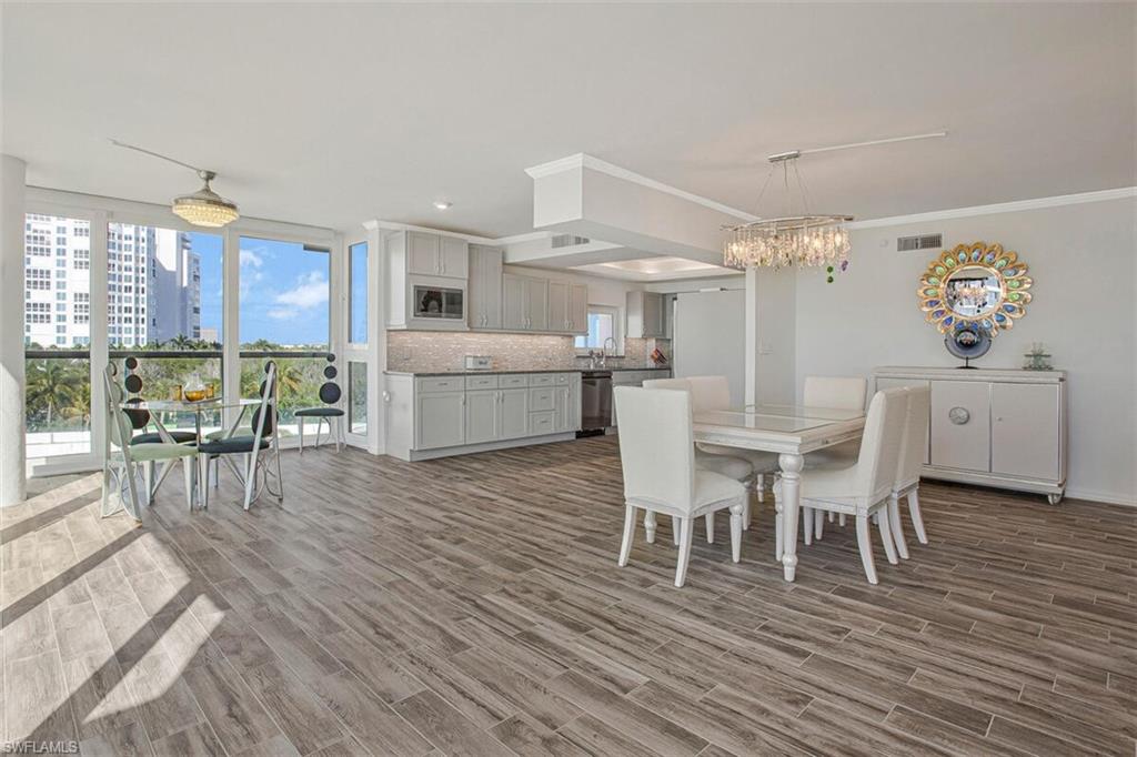 4031 Gulf Shore Boulevard North, Unit 6B Naples, FL 34103 - Photo 13 of 37 Dining area with wood finish floors, ornamental molding, a chandelier, a view of city, and recessed lighting