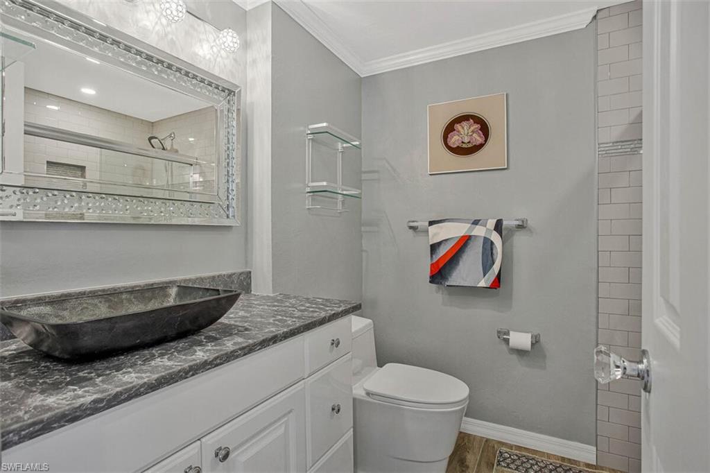 4031 Gulf Shore Boulevard North, Unit 6B Naples, FL 34103 - Photo 20 of 37 Bathroom with vanity, ornamental molding, a tile shower, and light wood-style flooring