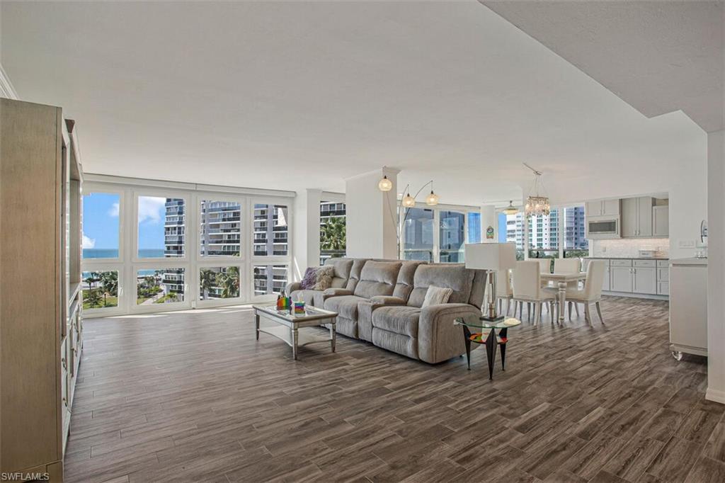 4031 Gulf Shore Boulevard North, Unit 6B Naples, FL 34103 - Photo 28 of 37 Living room featuring a chandelier and dark wood-type flooring