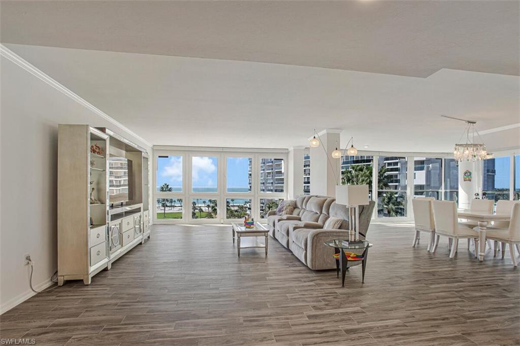 4031 Gulf Shore Boulevard North, Unit 6B Naples, FL 34103 - Photo 29 of 37 Living room with wood finished floors, a wall of windows, a chandelier, and ornamental molding